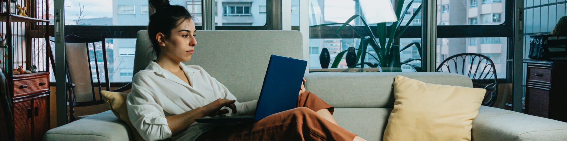 Vrouw zit op bank met laptop als afbeelding bij deeltijdpensioen