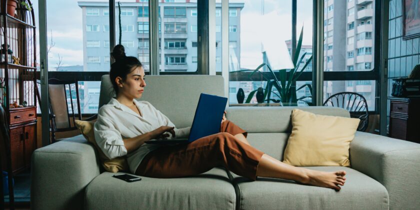 Vrouw zit op bank met laptop als afbeelding bij deeltijdpensioen