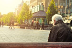 man zit op een bankje i een stad als afbeelding bij een blog over je pensioendatum kiezen