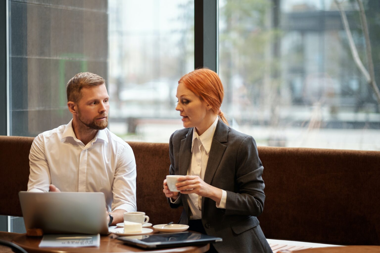 man en vrouw op een bank achter een computer, vrouw heeft koffie als afbeelding bij artikel over pensioenadviseur