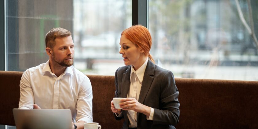 man en vrouw op een bank achter een computer, vrouw heeft koffie als afbeelding bij artikel over pensioenadviseur