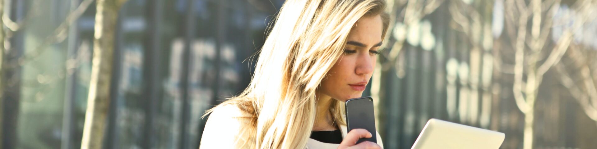 vrouw staat buiten en kijkt op haar tablet als afbeelding bij een blog over de AOW-leeftijd
