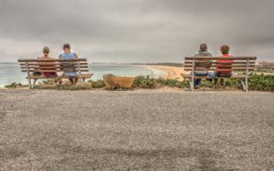 twee stellen zitten op een bankje bij het strand als afbeelding bij een blog over partnerpensioen als je partner jonger is
