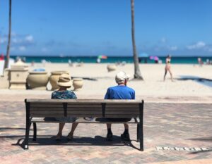 Ouder stel zit op bank bij het strand als illustratie bij uitruil partnerpensioen