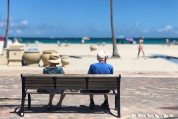Ouder stel zit op bank bij het strand als illustratie bij uitruil partnerpensioen