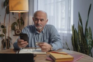 Man met telefoon koopt online als illustratie bij pensioen geïndexeerd