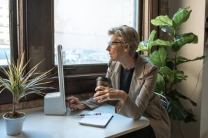 Vrouw met koffie achter computer als illustratie bij blog over zorgverzekering