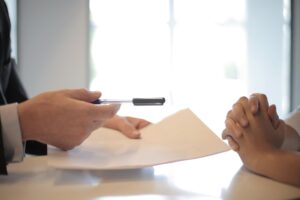 man geeft pen en document aan vrouw om te ondertekenen als afbeelding bij een blog over intentieverklaring pensioen