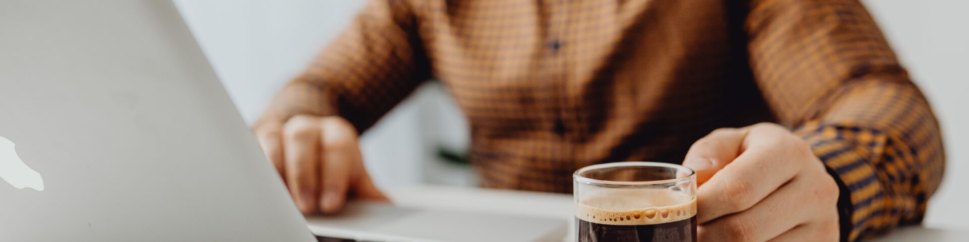 man achter een computer met een kop koffie als afbeelding bij een blog over AOW-bedragen per 1 juli 2023