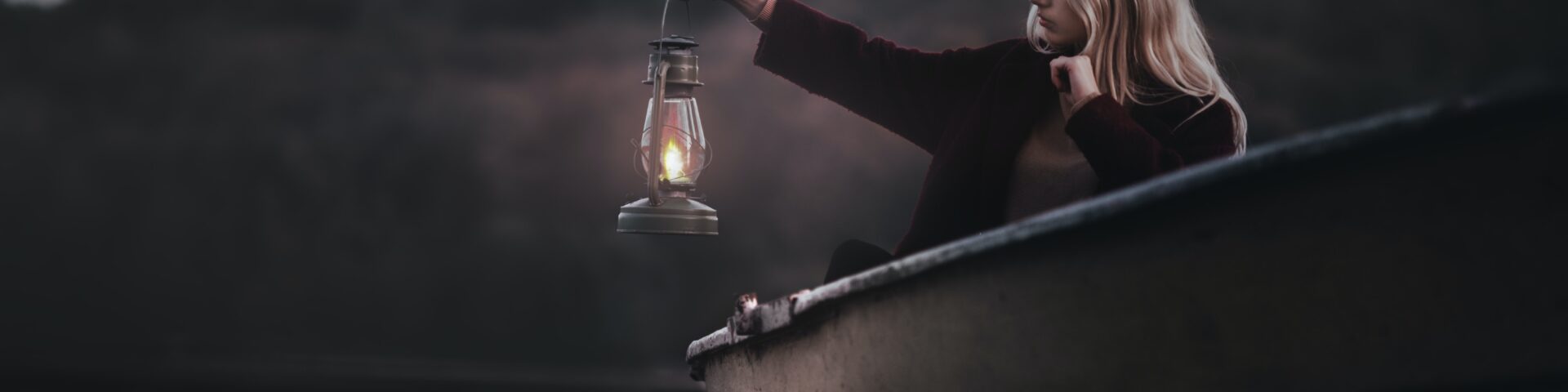Vrouw alleen in een roeiboot in de schemer met een lamp in haar hand als afbeelding bij een blog over de pensioendip