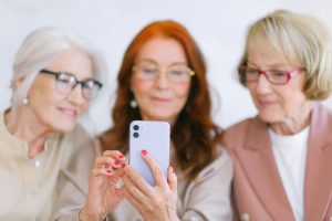 3 oudere dames kijken op een telefoon naar de AOW-bedragen per 1 juli 2024