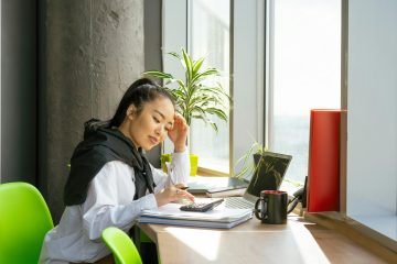 een vrouw maakt een berekening op een rekenmachine. Pensioen wordt lager als je eerder met pensioen gaat.