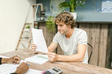 Man zit aan tafel en leest een papier, dit zou een transitieplan kunnen zijn in verband met eerder met pensioen en invaren