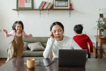 Vrouw werkt thuis met kinderen op de achtergrond als illustratie van een zwaar beroep bij RVU-regeling verlengen