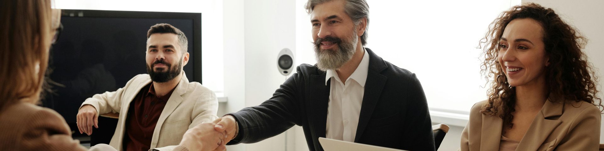 Man geeft een handdruk tijdens een setting aan een bureau met meerdere mensen als illustratie bij RVU-regeling en transitievergoeding